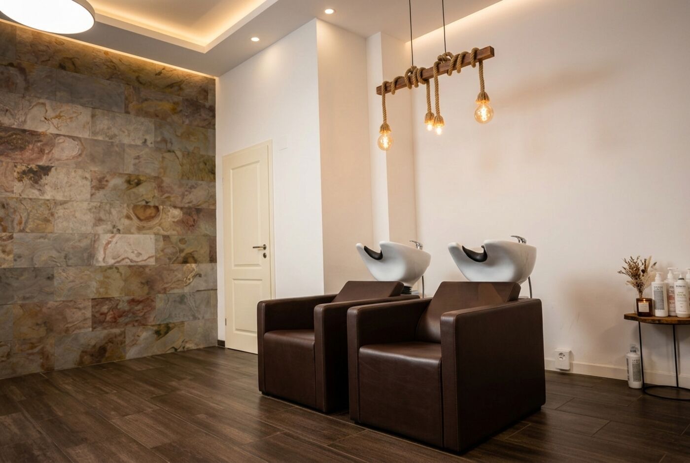 Waschplätze im Salon HAARVOLL mit Natursteinwand und warmem Licht